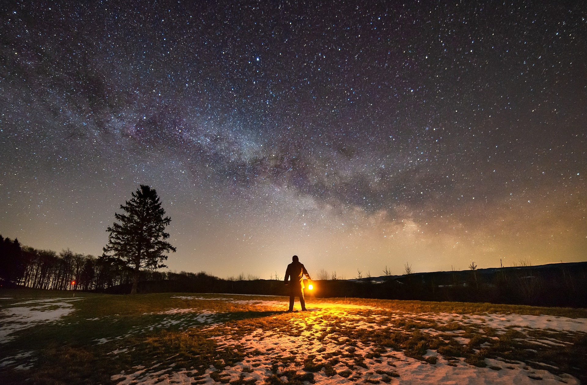 満天星空の中、一人たたずむ人の写真。